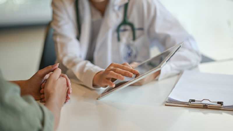 A doctor holding an ipad talking to a patient